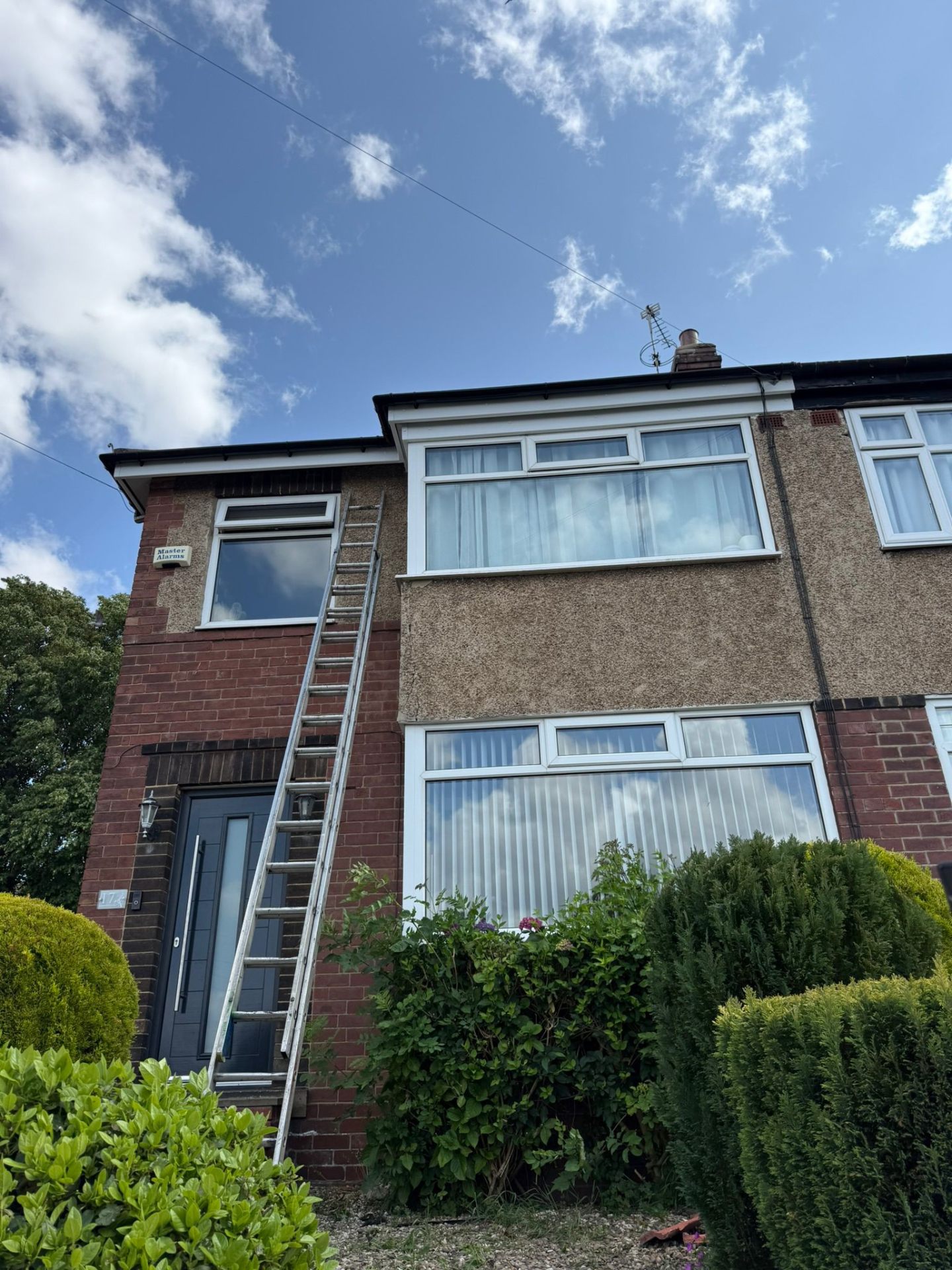Roofer accessing semi-detached roof via ladder for repairs